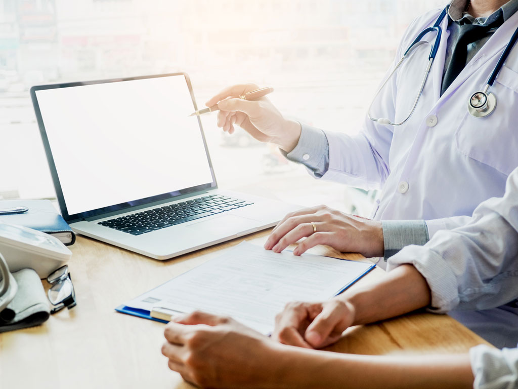 Doctor consulting with patient presenting results on blank Screen tablet computer sitting at table